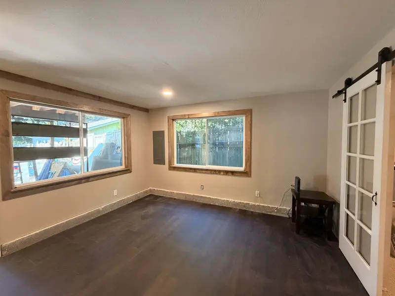 Finished room with new dark plank flooring, stained wood window trim and a sliding door