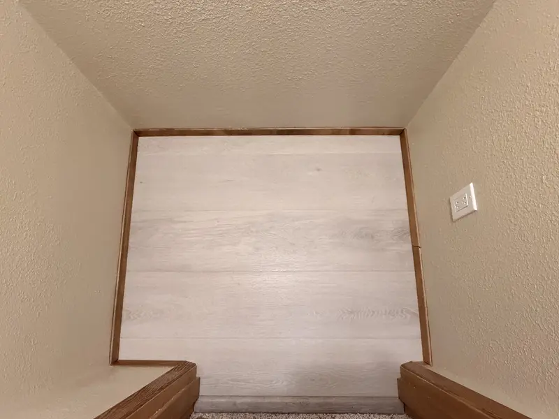 New light plank flooring with wood trim inside the closet