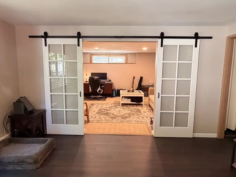 Finished wall with two white glass-panel barn doors open onto a home office