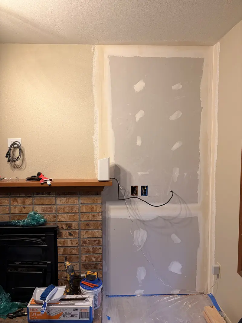 New drywall patched and taped in an alcove beside a brick fireplace
