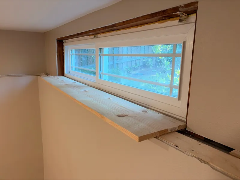 Basement window with exposed foam and no trim before the work