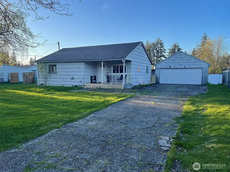 Single-story house with a covered porch and a detached garage on a large lawn