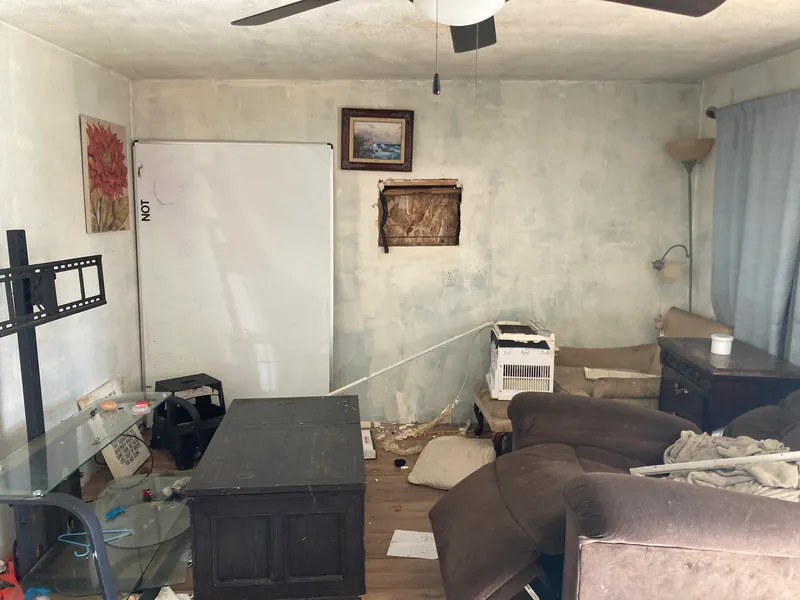Living room filled with furniture and clutter, with a ceiling fan overhead