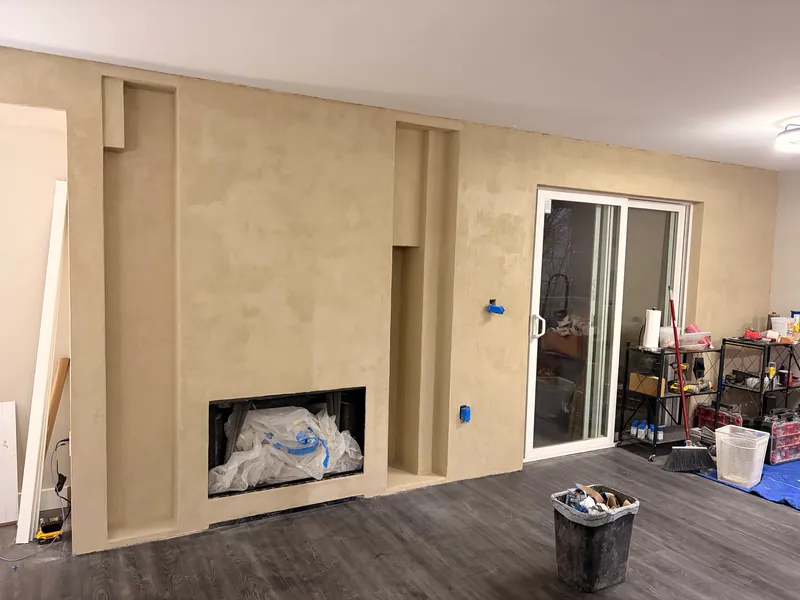 Fireplace and kitchen wall mid-way through a wall finish