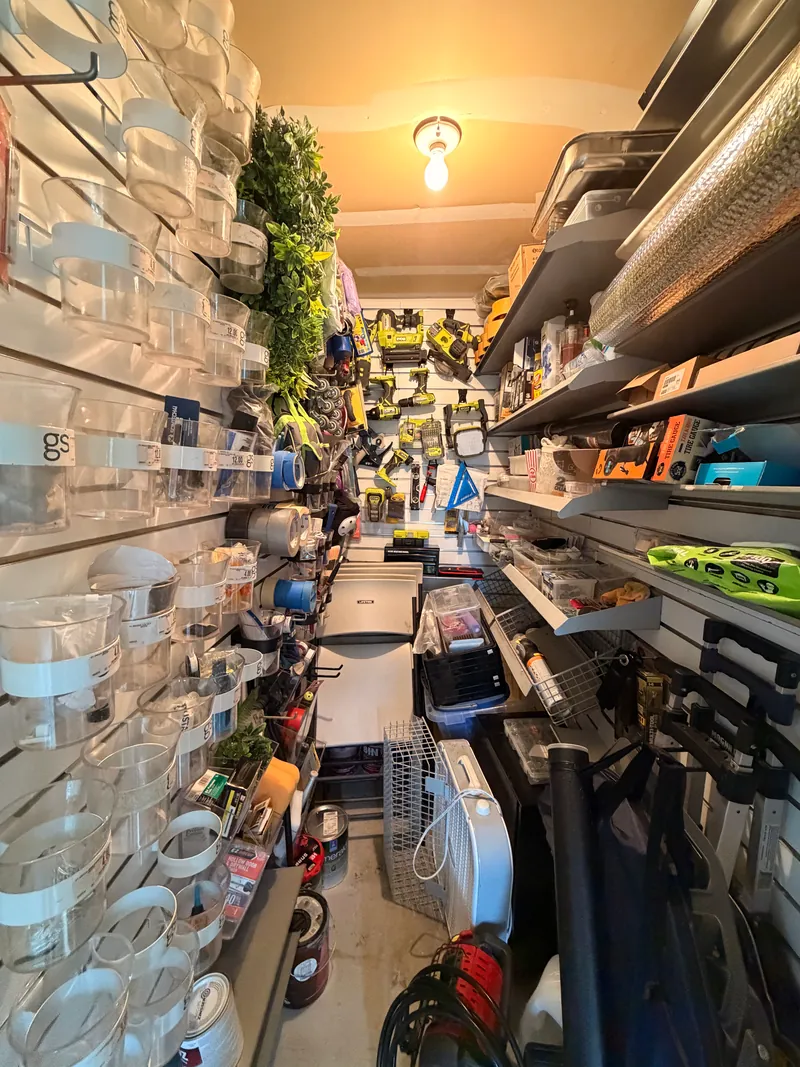 Narrow storage room with floor-to-ceiling shelving and organized bins