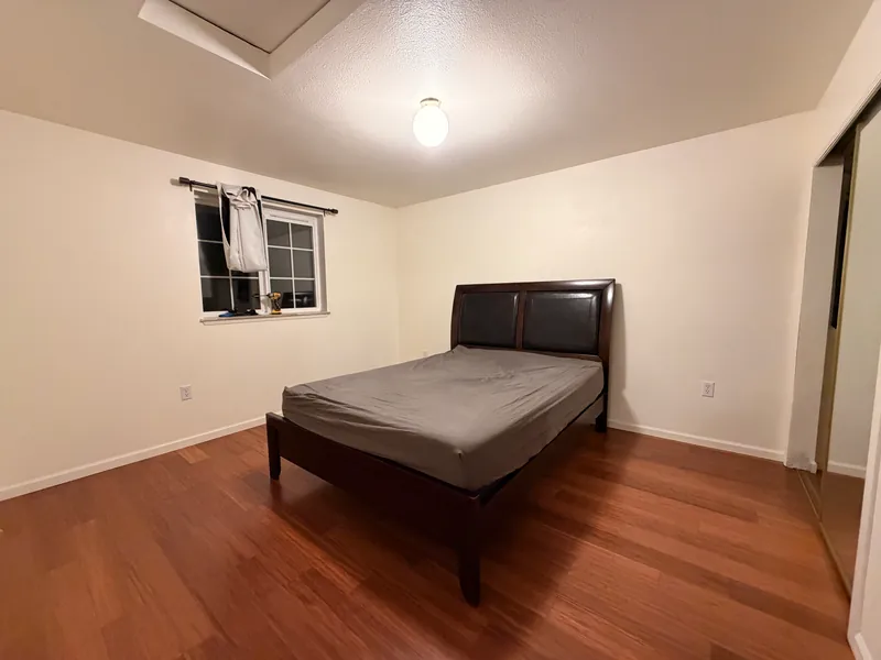 Bedroom with a dark bed and new warm-toned plank flooring