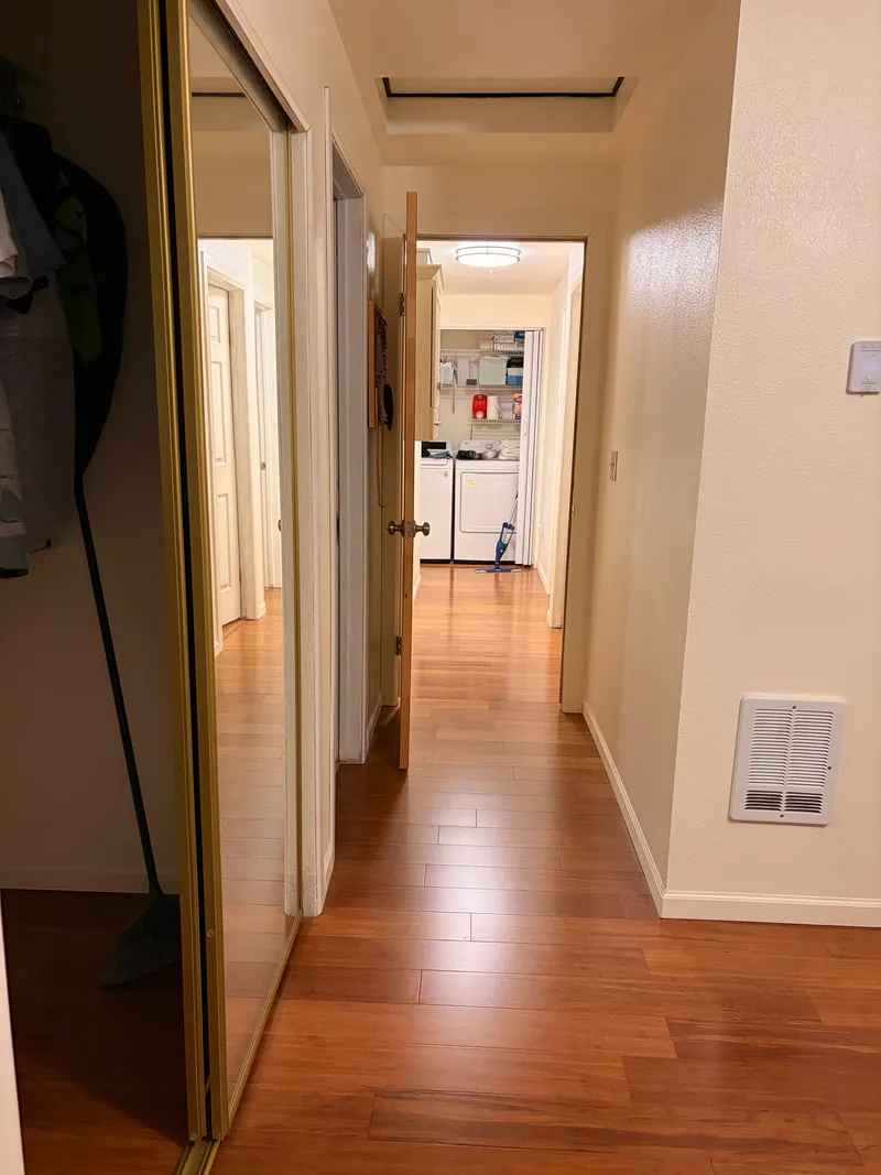 Long hallway with mirrored closet doors and new plank flooring