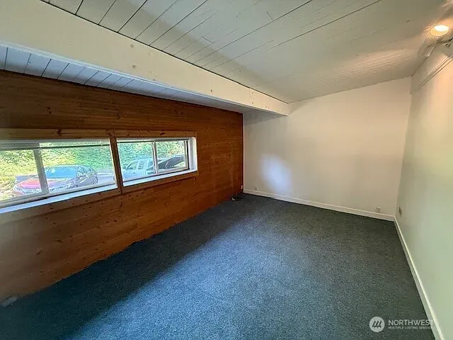 Empty bedroom with fresh white walls, wood paneling, a clerestory window and clean carpet