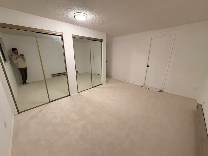 Renovated bedroom with fresh white walls, mirrored closet doors and new carpet
